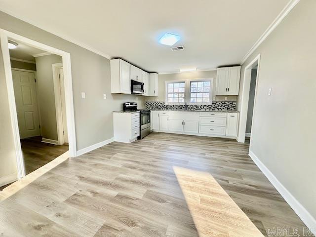 kitchen with stainless steel electric range, visible vents, white cabinets, and ornamental molding