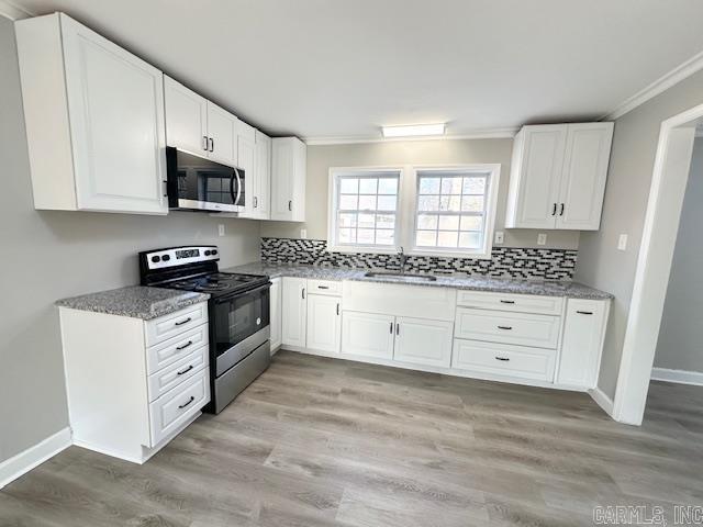 kitchen with light wood-style floors, appliances with stainless steel finishes, backsplash, and a sink