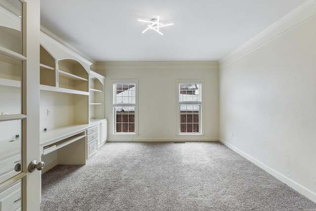 empty room featuring carpet floors, baseboards, ornamental molding, and built in study area