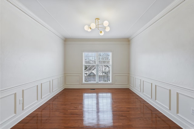 empty room featuring wood finished floors, a decorative wall, and an inviting chandelier