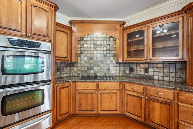 kitchen featuring brown cabinets, double oven, black electric cooktop, and a warming drawer