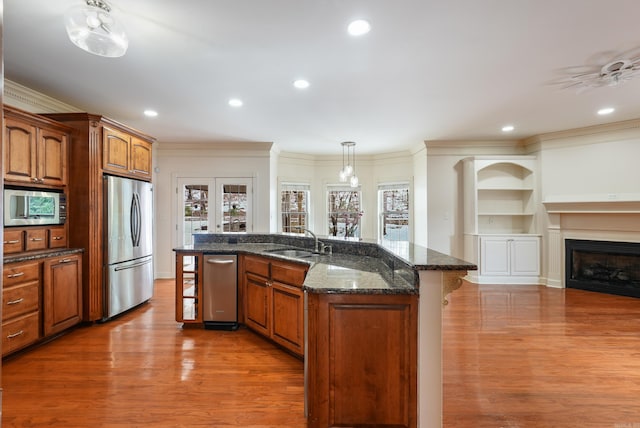 kitchen featuring light wood-style flooring, a fireplace, a sink, appliances with stainless steel finishes, and a kitchen bar