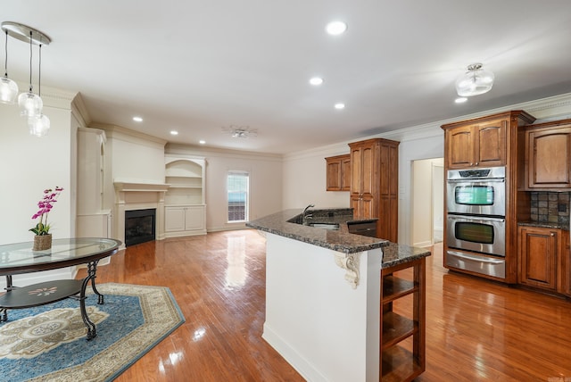 kitchen featuring double oven, brown cabinetry, a warming drawer, and a kitchen bar