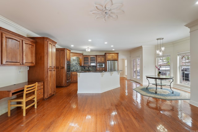 kitchen with appliances with stainless steel finishes, brown cabinetry, ornamental molding, and light wood finished floors