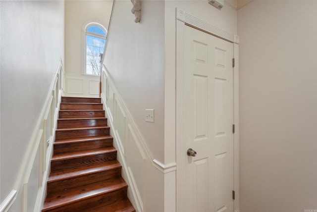 staircase featuring wainscoting and a decorative wall