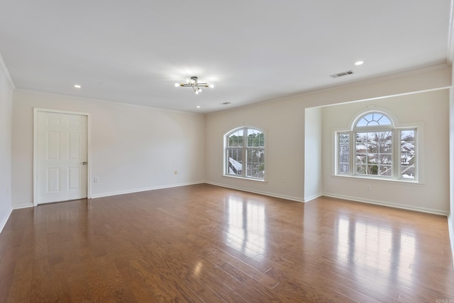 unfurnished room with crown molding, wood finished floors, visible vents, and baseboards