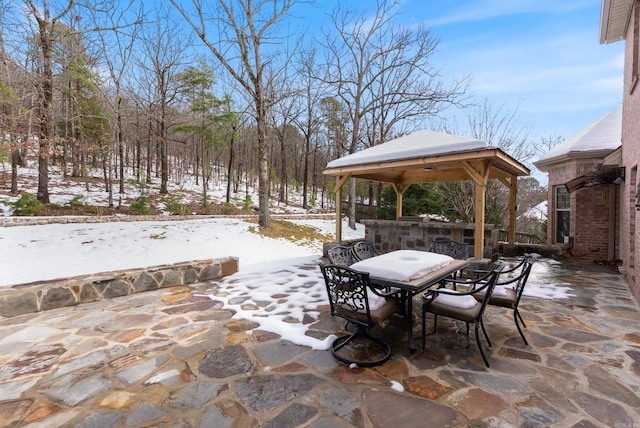 snow covered patio featuring outdoor dining space and a gazebo