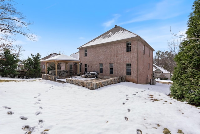 snow covered property with brick siding and a gazebo