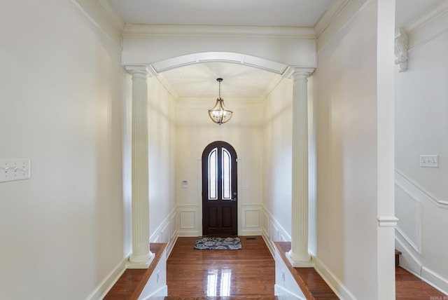 entryway featuring ornate columns, arched walkways, a decorative wall, and wood finished floors