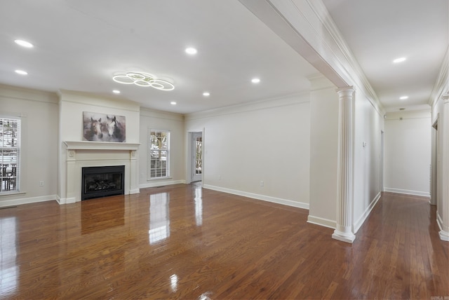 unfurnished living room with ornate columns, a fireplace, ornamental molding, and wood finished floors