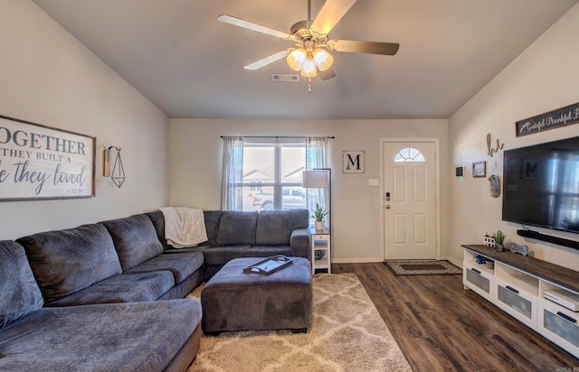 living room featuring a ceiling fan, visible vents, baseboards, and wood finished floors