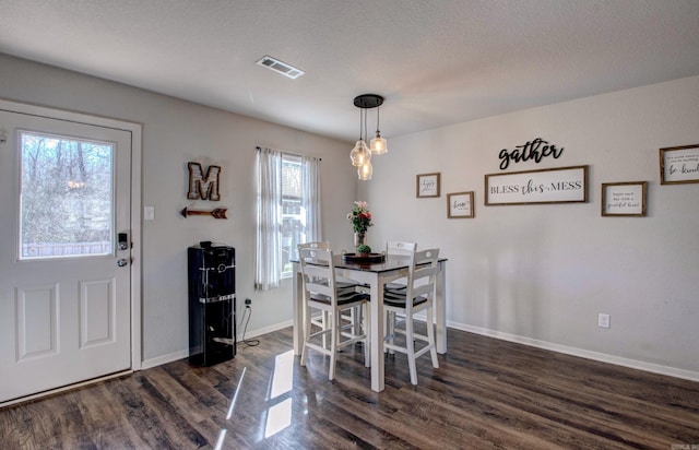 dining space featuring dark wood-type flooring, visible vents, a textured ceiling, and baseboards