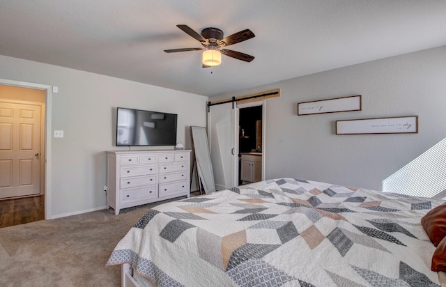 carpeted bedroom with a barn door, baseboards, and ceiling fan