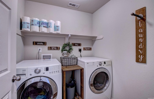 washroom with a textured ceiling, laundry area, washing machine and clothes dryer, and visible vents