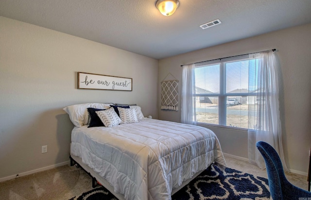 bedroom featuring carpet, visible vents, a textured ceiling, and baseboards