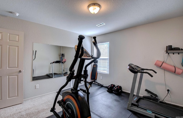 workout area featuring baseboards, visible vents, a textured ceiling, and a textured wall