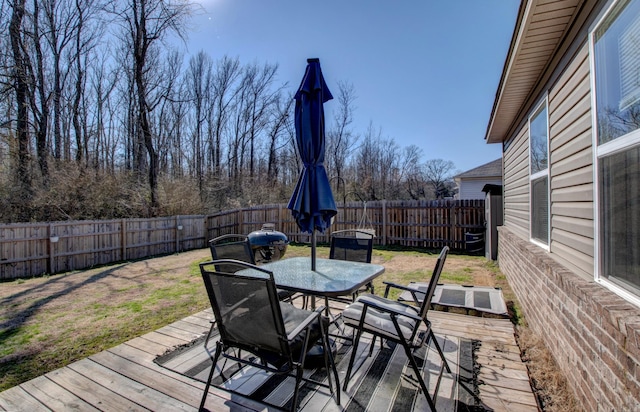 wooden terrace with outdoor dining space, a fenced backyard, and a lawn