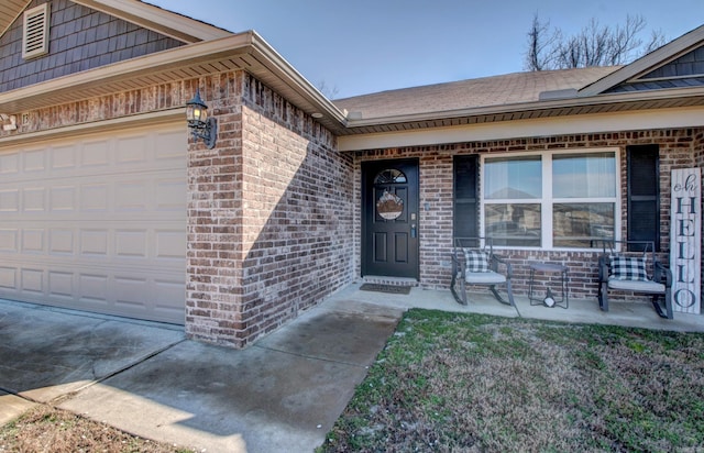 property entrance featuring a garage, a porch, and brick siding