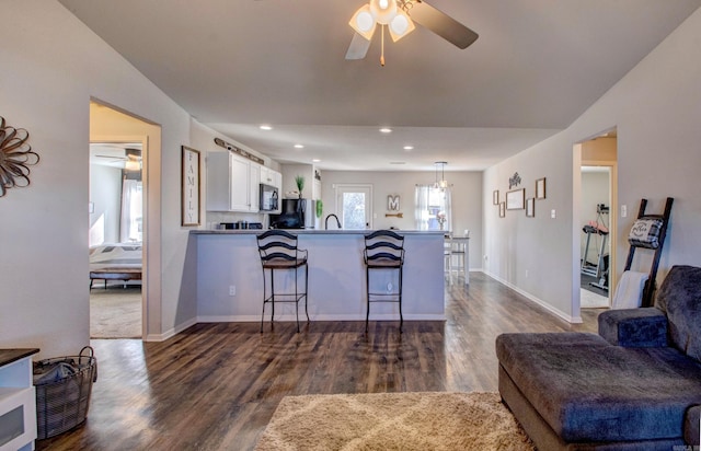 kitchen featuring stainless steel microwave, open floor plan, freestanding refrigerator, a peninsula, and white cabinetry