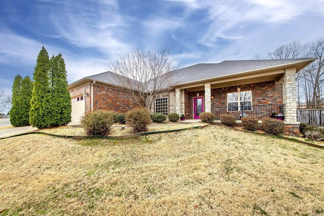 ranch-style house featuring a porch, a garage, brick siding, roof with shingles, and a front yard