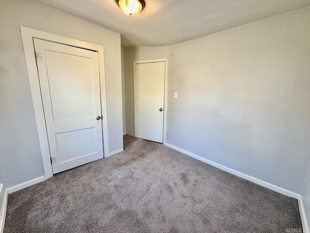 unfurnished bedroom with carpet floors, baseboards, and a closet