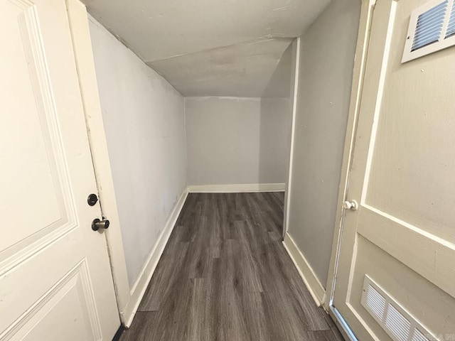 corridor with dark wood-type flooring, visible vents, and baseboards