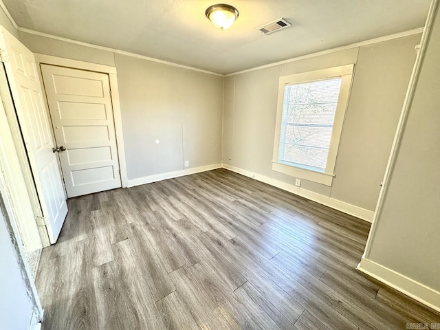 empty room with baseboards, dark wood-style flooring, visible vents, and crown molding