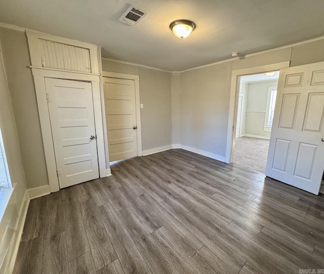 unfurnished room featuring dark wood-style floors, visible vents, crown molding, and baseboards