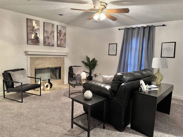 carpeted living area with a textured ceiling, ceiling fan, a premium fireplace, and baseboards