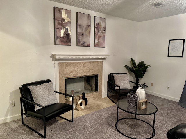 living area featuring baseboards, visible vents, a textured ceiling, carpet floors, and a fireplace