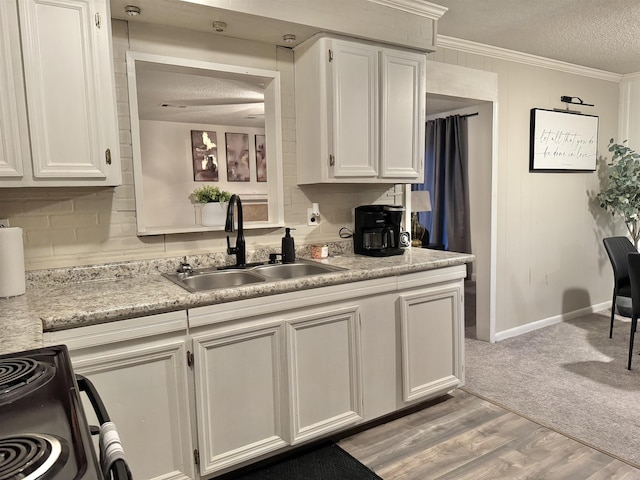 kitchen with a textured ceiling, a sink, light countertops, gas stove, and crown molding