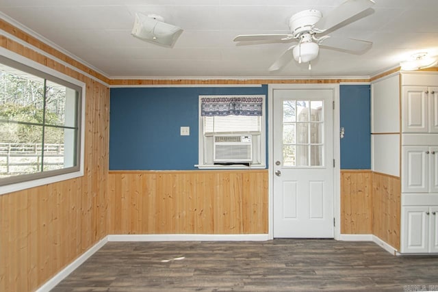 interior space featuring ceiling fan, wood walls, wainscoting, dark wood finished floors, and crown molding