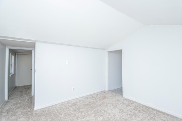 unfurnished room with light carpet, baseboards, and vaulted ceiling