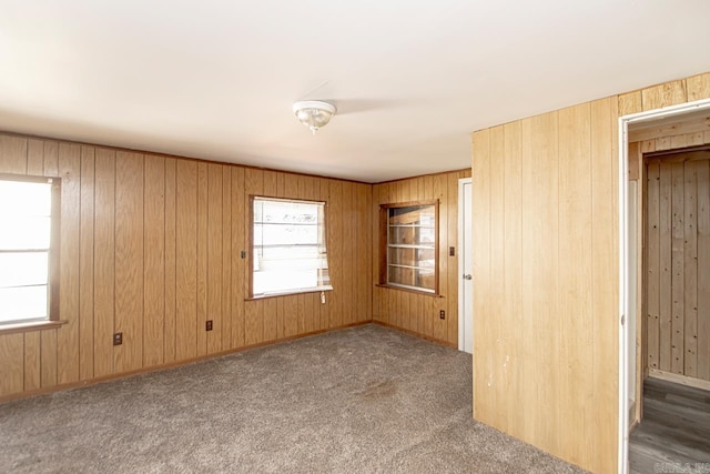 unfurnished room with wood walls, baseboards, and carpet flooring