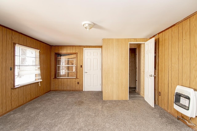 carpeted empty room with wood walls and heating unit