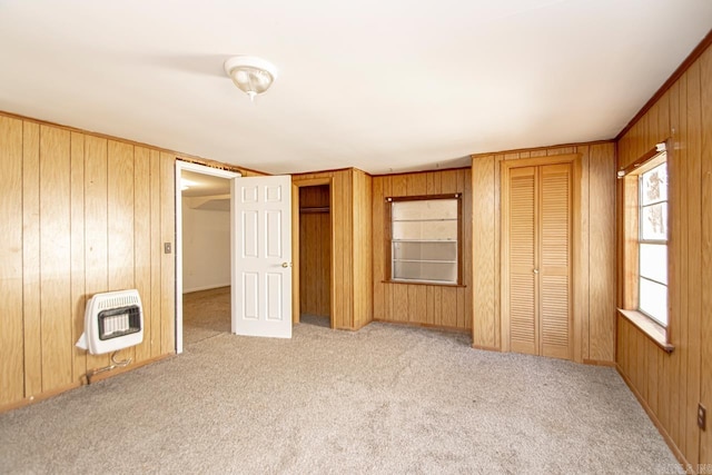 unfurnished bedroom featuring heating unit, wood walls, and carpet flooring