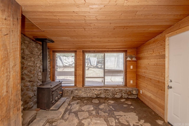 empty room featuring a wood stove, wooden ceiling, and vaulted ceiling