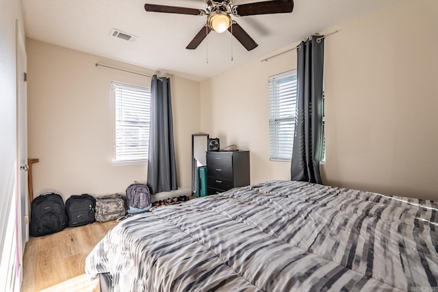 bedroom featuring ceiling fan, visible vents, and wood finished floors