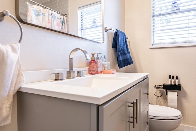 bathroom with curtained shower, plenty of natural light, vanity, and toilet