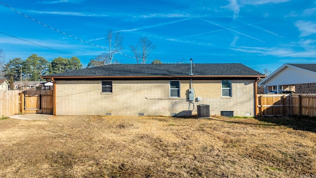 back of house with central AC unit, brick siding, fence, a yard, and crawl space