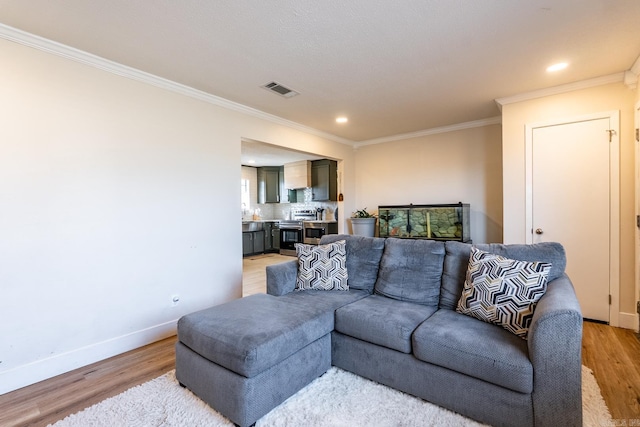 living room with recessed lighting, visible vents, baseboards, ornamental molding, and light wood finished floors