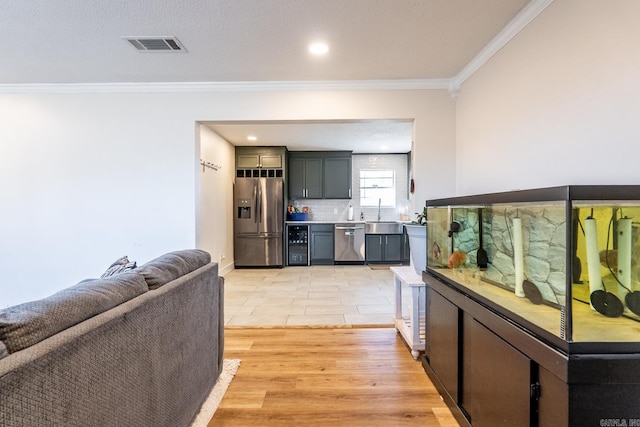 kitchen featuring crown molding, tasteful backsplash, visible vents, appliances with stainless steel finishes, and a sink