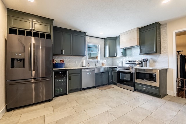 kitchen with tasteful backsplash, wine cooler, appliances with stainless steel finishes, and a sink