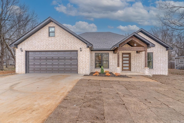 view of front of home featuring a garage, a shingled roof, concrete driveway, and brick siding