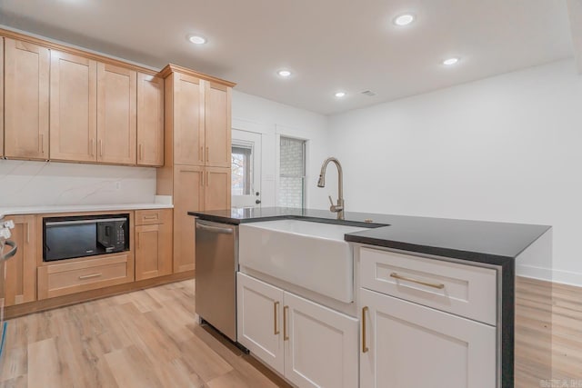 kitchen featuring light wood-style floors, black microwave, a sink, and stainless steel dishwasher