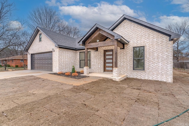 view of front of house with a garage, brick siding, driveway, and roof with shingles