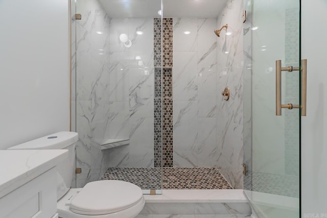 bathroom featuring toilet, a marble finish shower, and vanity