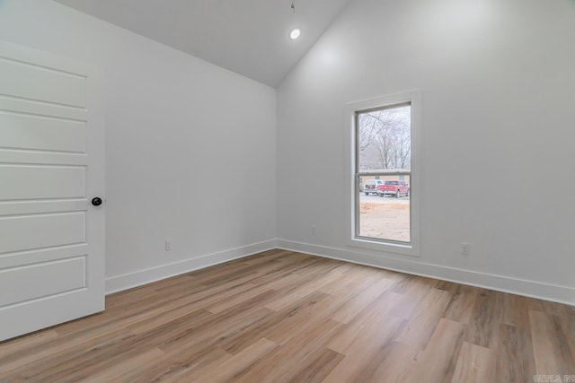 spare room featuring high vaulted ceiling, recessed lighting, light wood-style flooring, and baseboards