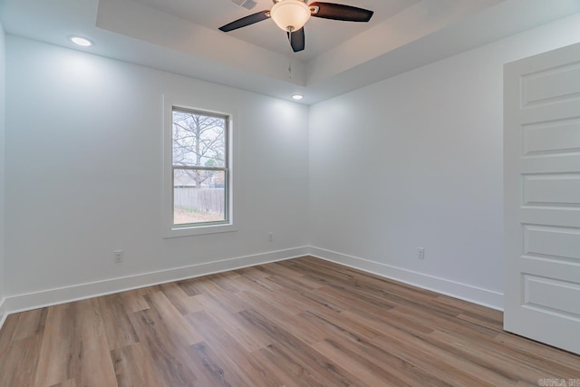 unfurnished room featuring recessed lighting, a raised ceiling, a ceiling fan, light wood-type flooring, and baseboards