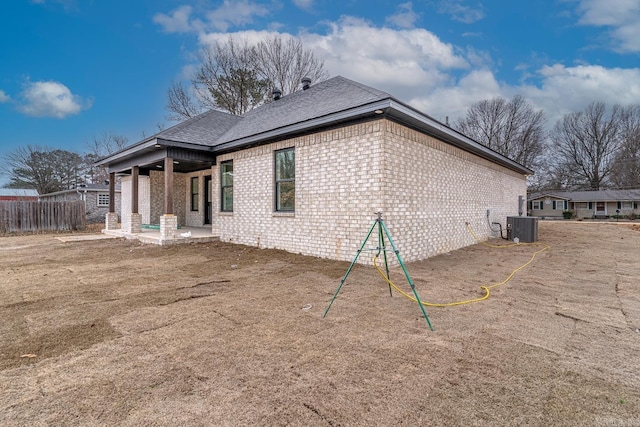 view of home's exterior with a patio area, brick siding, fence, and central AC unit